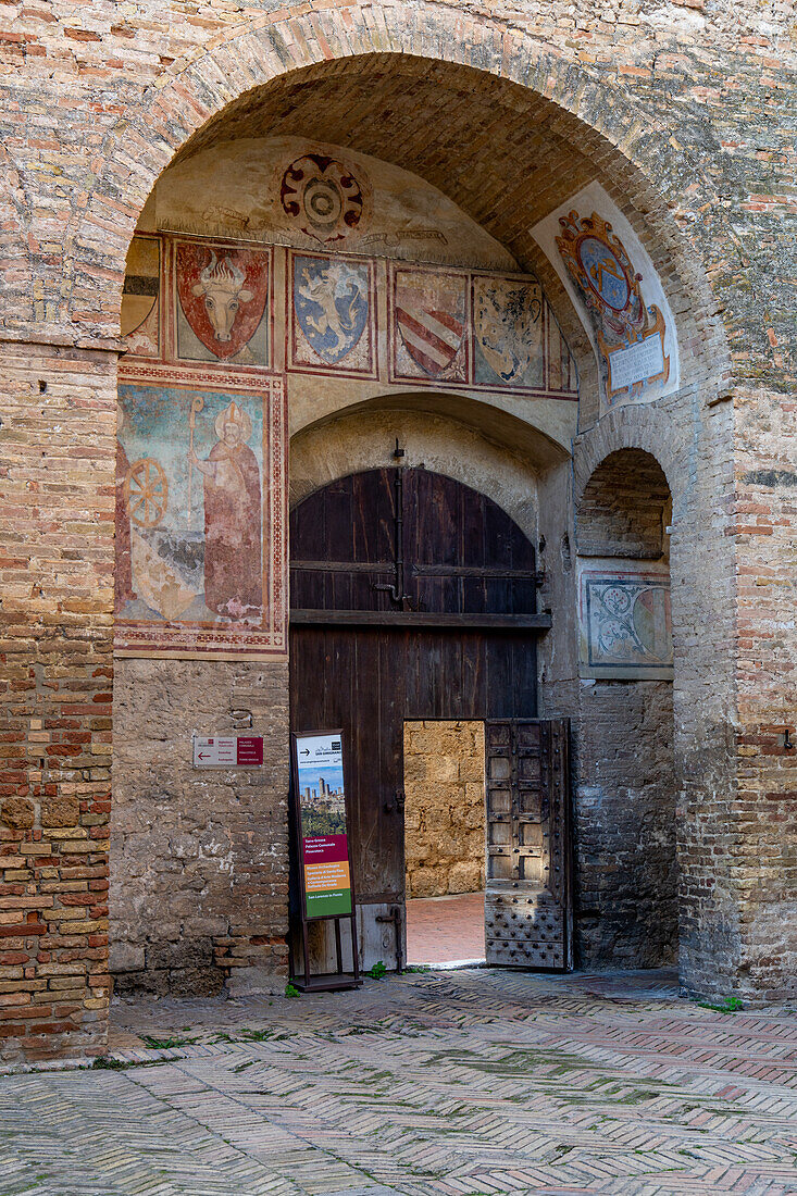 Medieval coats of arms over the doorway to the courtyard of the Palazzo Comunale or city hall in San Gimignano, Italy.