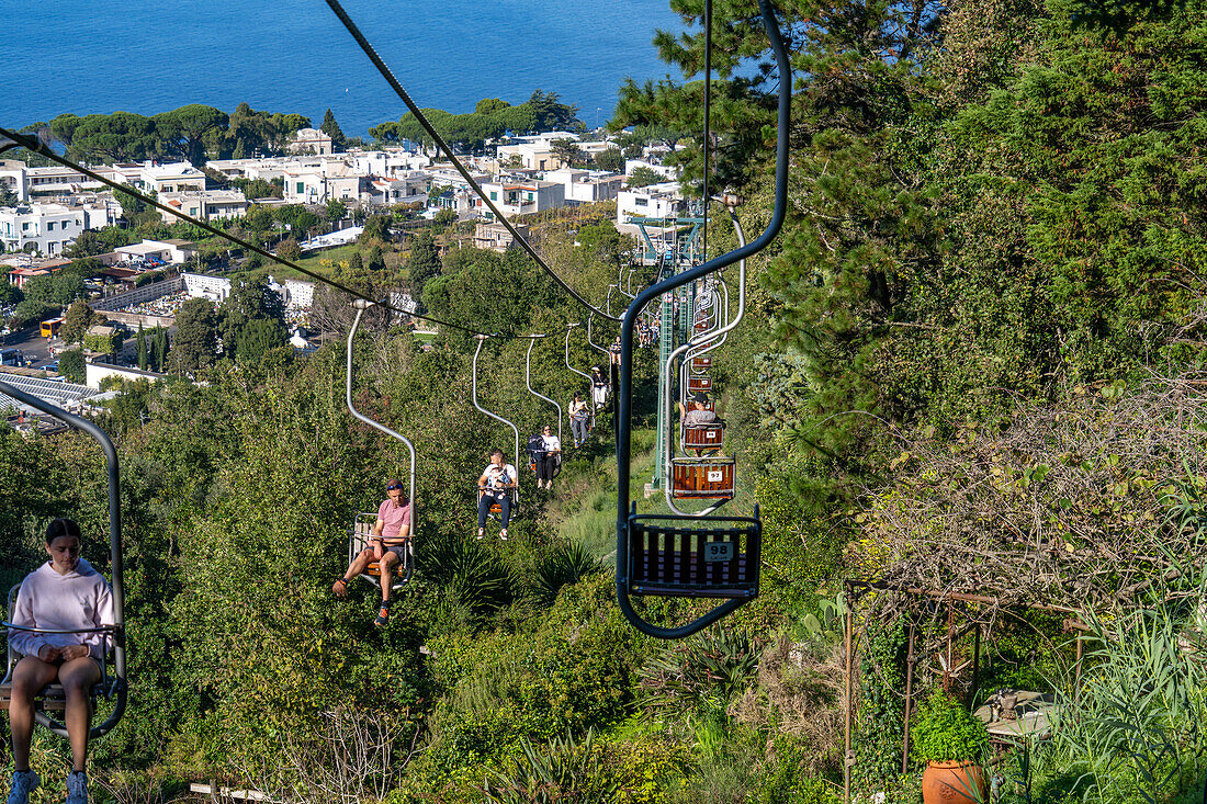 Touristen auf dem Monte Solaro Sessellift von Anacapri zum Monte Solaro Aussichtspunkt auf der Insel Capri, Italien. Die Stadt Anacapri ist unterhalb zu sehen.