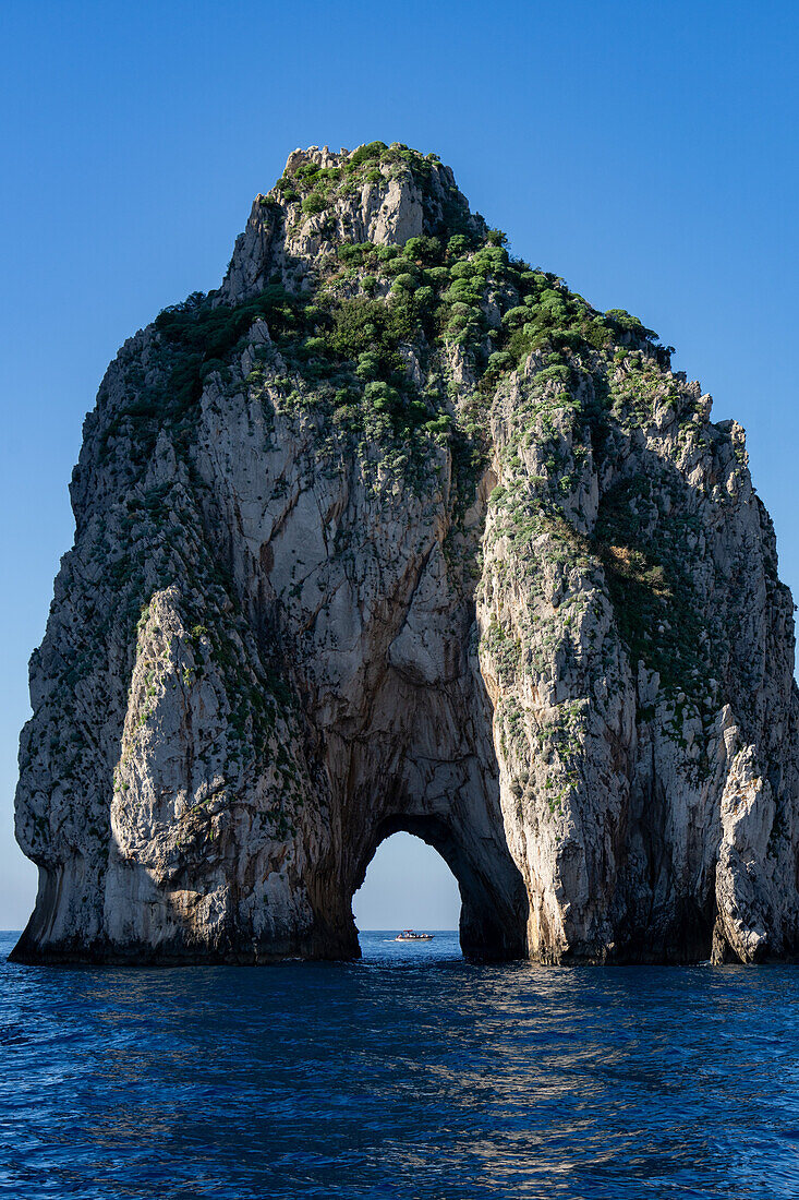 The Farallons or faraglioni, sea stacks off the coast of the island of Capri, Italy. Mezzo, with a boat visible through its sea arch.