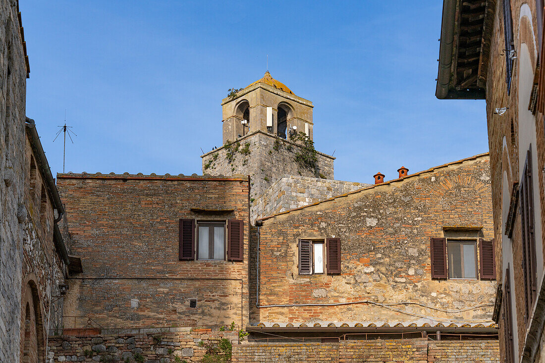 The top of the Torre Rognosa above buildings on Via San Giovanni in the medieval city of San Gemignano, Italy.