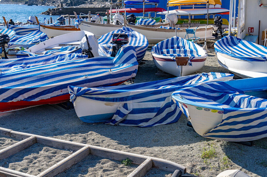 Boote mit gestreiften Planen am Strand in der Nebensaison in Monterosso al Mare, Cinque Terre, Italien.