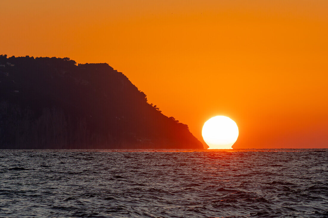 Sonnenuntergang über dem Meer vor der Insel Capri in der Bucht von Neapel, Italien.