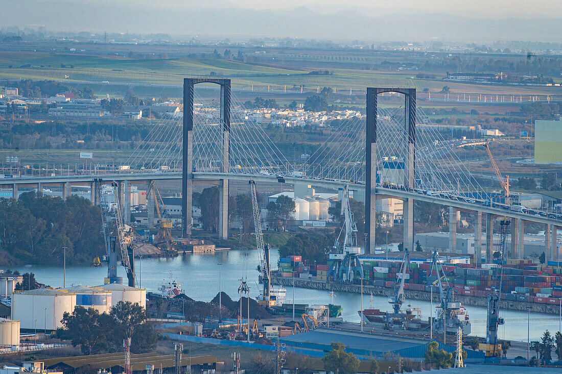 A detailed aerial perspective showcasing the Centenary Bridge and bustling seaport of Seville during the twilight hours.