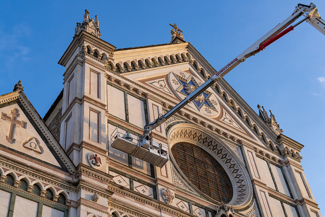 Arbeiter reinigen mit einem Aufzug die Fassade der Basilika Santa Croce oder Basilika des Heiligen Kreuzes in Florenz, Italien.