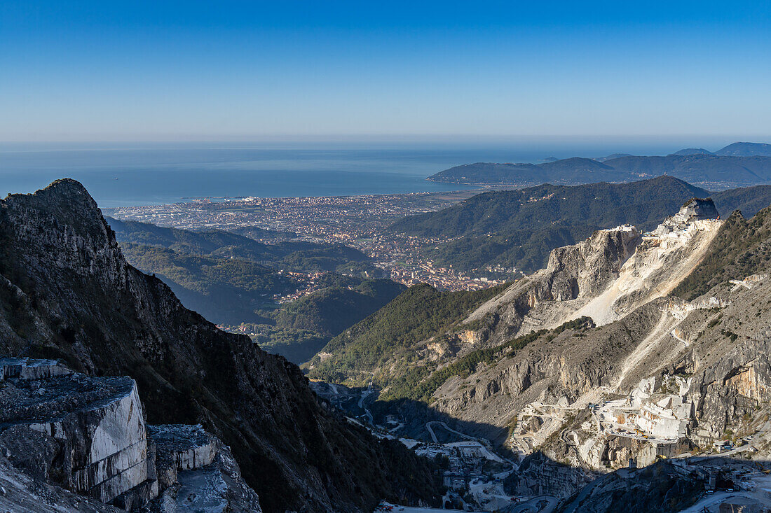 Blick auf die Marmorsteinbrüche des Fantiscritti-Beckens bei Carrara, Italien. Carrara und das Lingurische Meer liegen im Hintergrund.