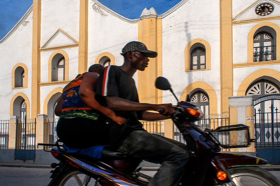 Einheimische auf einem Motorrad und die Häuser der Kirche Église Baptiste Tabernacle in der historischen kolonialen Altstadt von Jacmel, Haiti, Westindien, Karibik, Mittelamerika