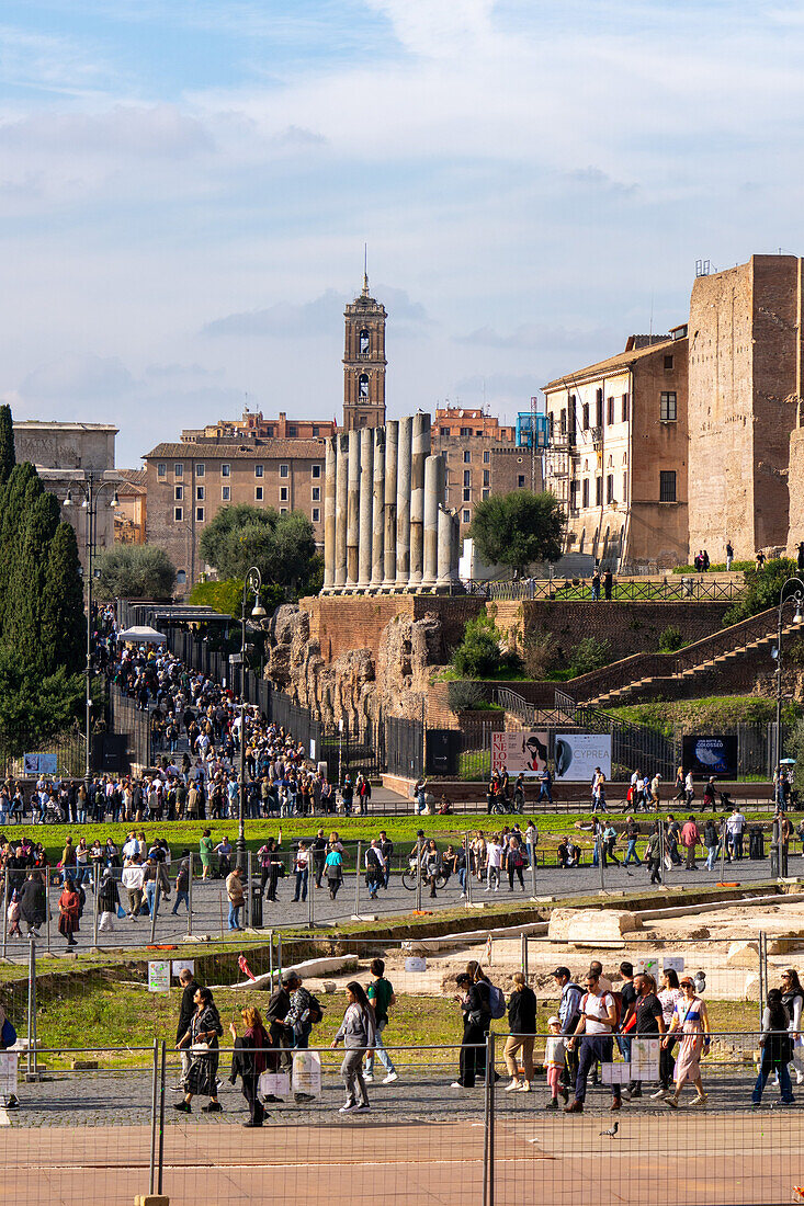 Römische Säulen entlang der Via Sacra im archäologischen Park des Kolosseums mit dem Turm des Palazzo Senatorio in Rom, Italien.