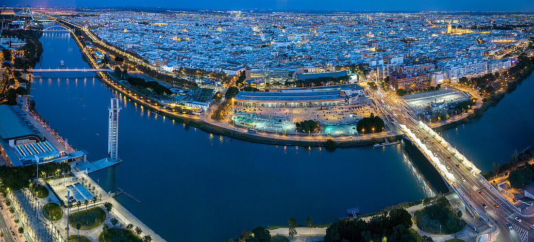 Das Abendlicht wirft einen warmen Schein auf den Fluss Guadalquivir und die historischen Gebäude in Sevilla und zeigt das pulsierende Stadtbild.