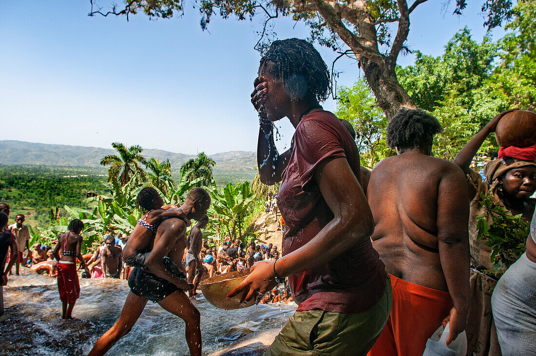 Haiti Voodoo Festival in Saut d'Eau, in Saut d'Eau, Ville Bonheur, Haiti. Tausende von Vodou- und katholischen Anhängern versammelten sich unter dem Wasserfall von Saut d'Eau in Haiti. Die Wallfahrt, die sowohl von Voodou-Anhängern als auch von Katholiken unternommen wird, hat ihren Ursprung in der Sichtung des Bildes der Jungfrau Maria auf einem Palmblatt in der Nähe des Wasserfalls vor einem halben Jahrhundert. Der Katholizismus und die Voodou-Praktiken sind in ihrer haitianischen Form für immer miteinander verwoben. Das Erscheinen eines Regenbogens unter den Wasserfällen soll bedeuten, dass