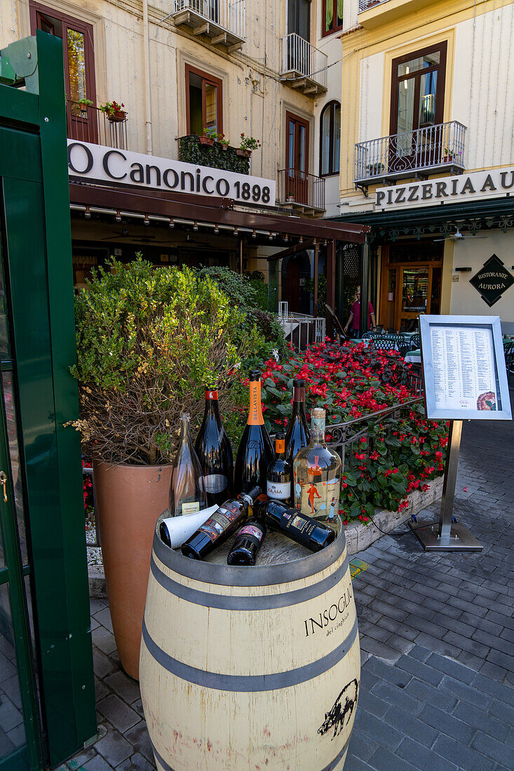 Weinflaschen auf einem Weinfass vor einem Restaurant im historischen Zentrum von Sorrento, Italien.