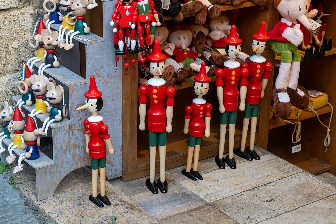 Pinocchio-Holzpuppen zum Verkauf in einem Geschäft in der Via San Giovanni in der mittelalterlichen Stadt San Gimignano, Italien.