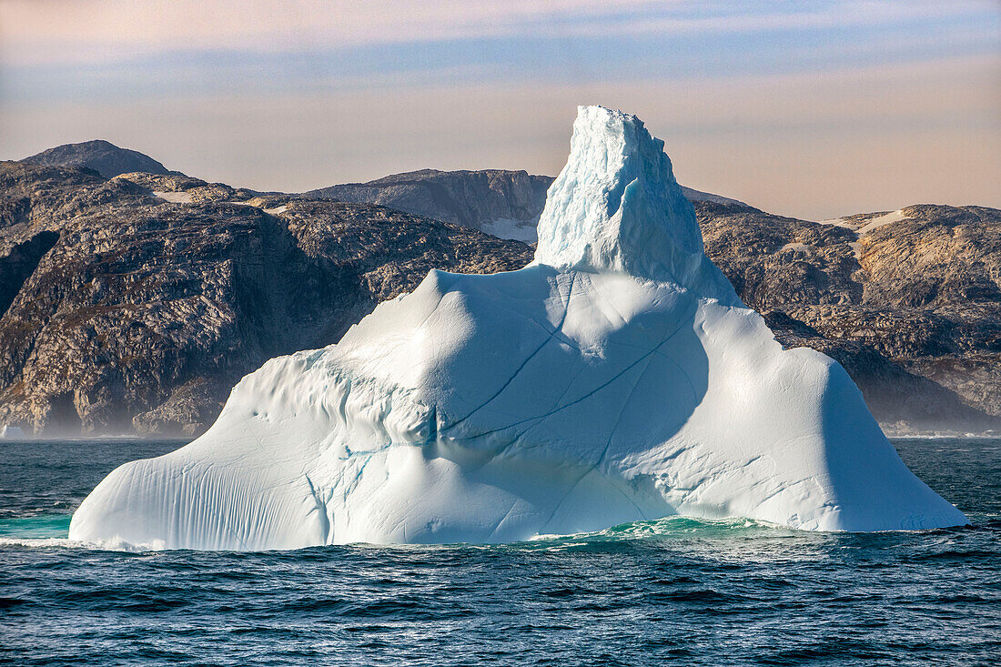 Kangerlussuaq Fjord. Large iceberg in scenic fjord surrounded by snow-capped mountains, Southeast coast, Greenland