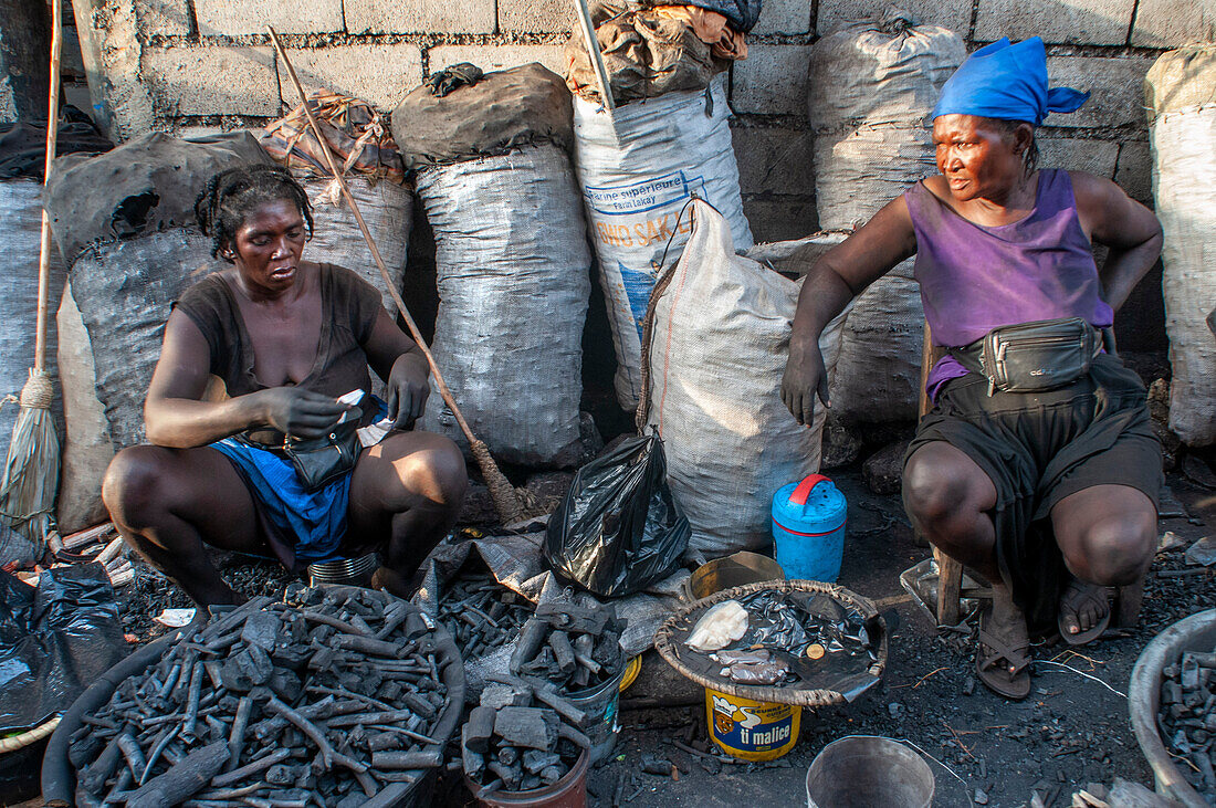 Woman selling coal charcoal in the local market and houses in the historic colonial old town, Jacmel city center, Haiti, West Indies, Caribbean, Central America