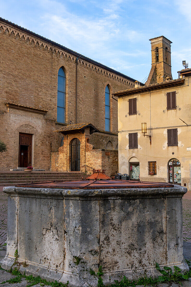 The well or cistern in the Piazza San Agostino with the Church of San Agostino behind. San Gimignano, Italy.