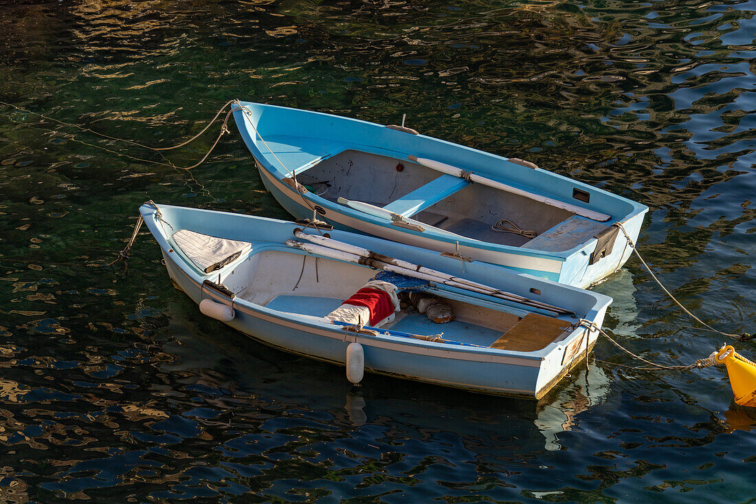 Zwei kleine Ruderboote liegen im Hafen von Riomaggiore, Cinque Terre, Italien.