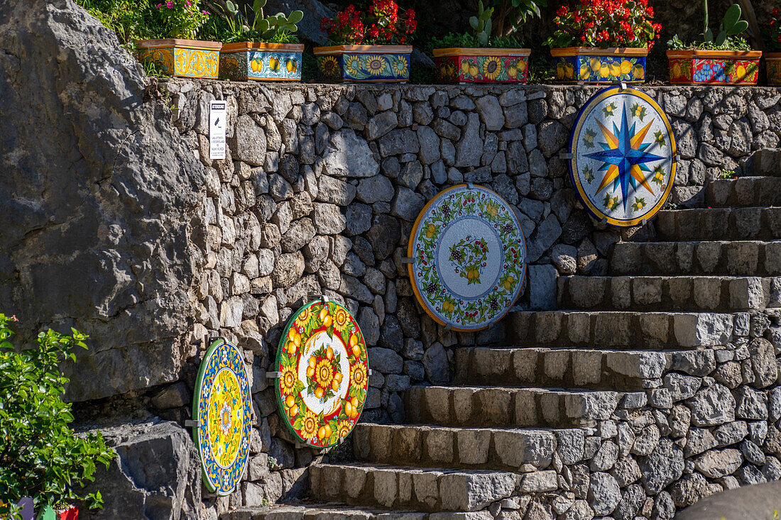 Large, colorful ceramic tabletops decorate a stone staircase at a ceramic shop on the Amalfi Coast of Italy.