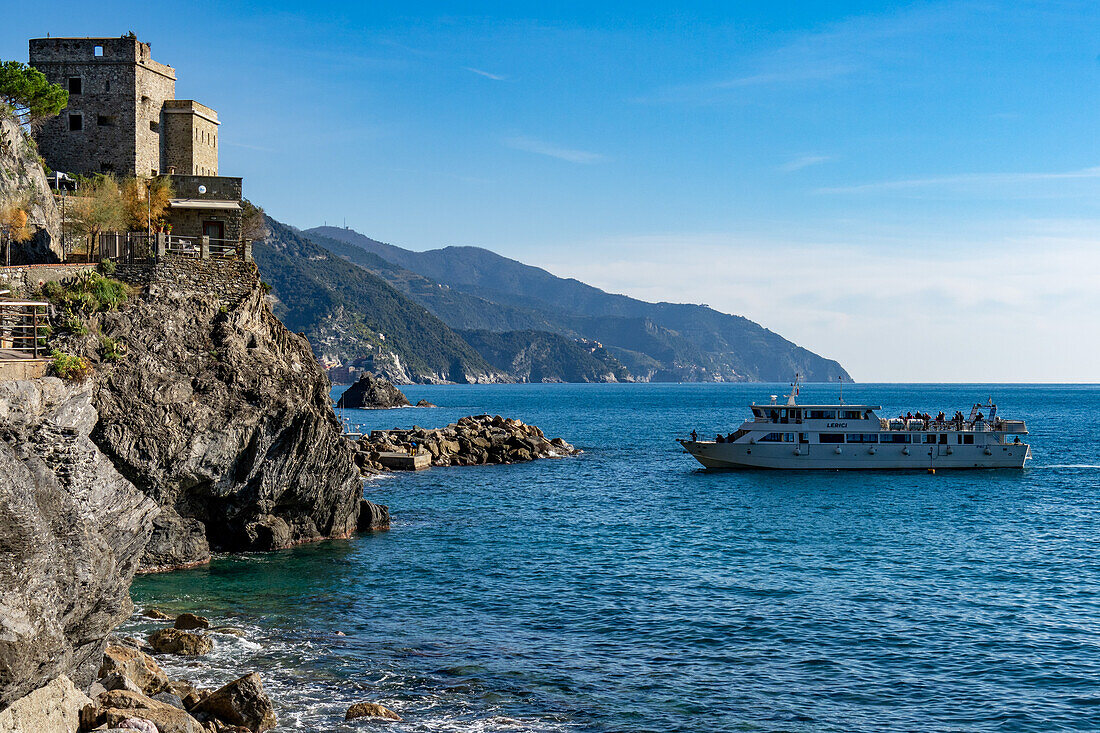 Eine Passagierfähre legt unterhalb des mittelalterlichen Aurora-Turms in Monterosso al Mare, Cinque Terre, Italien, an.