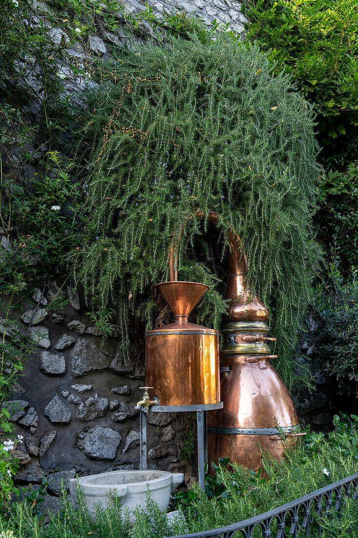 Vintage copper vessels used in the making of perfumes in the garden of a perfumery in Capri, Italy.