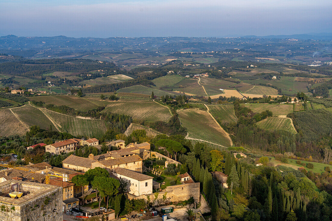 Agricultural land with grape vinyards & olive orchards behind the rooftops of San Gimignano, Italy.