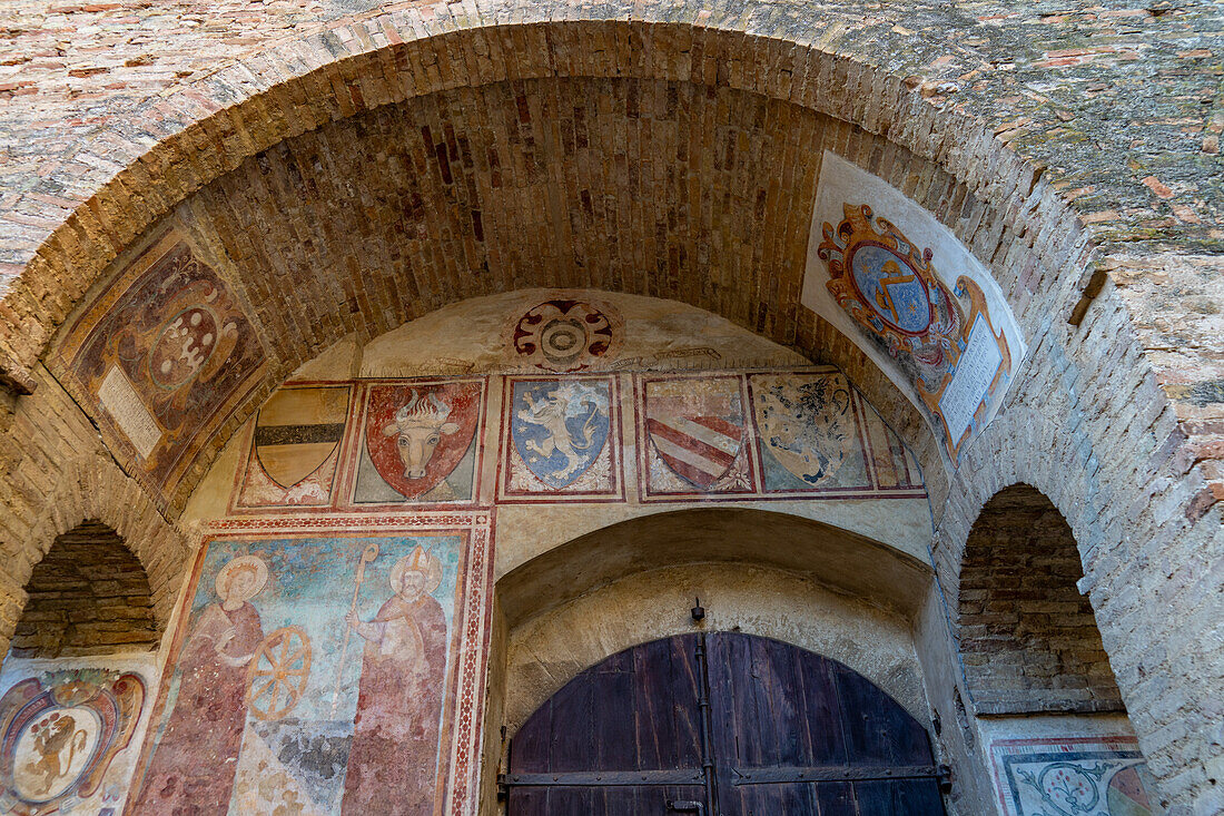 Medieval coats of arms over the doorway to the courtyard of the Palazzo Comunale or city hall in San Gimignano, Italy.