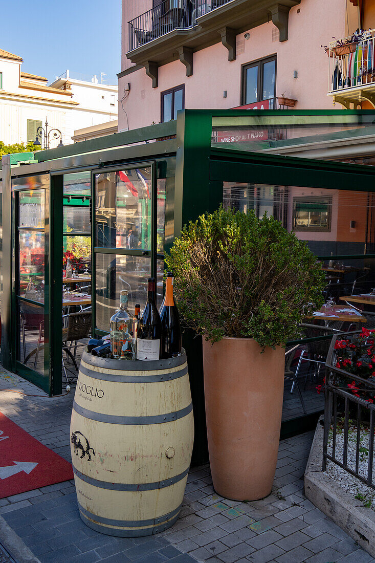 Wine bottles on a wine barrel in front of a restaurant in the historic center of Sorrento, Italy.