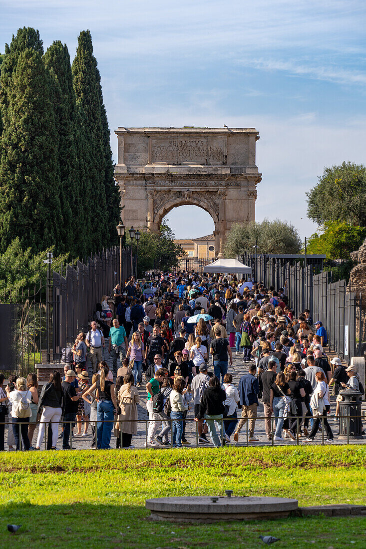 Tourists on the Via Sacra going toward the Arch of Titus in the Colosseum Archaeological Park, Rome, Italy.