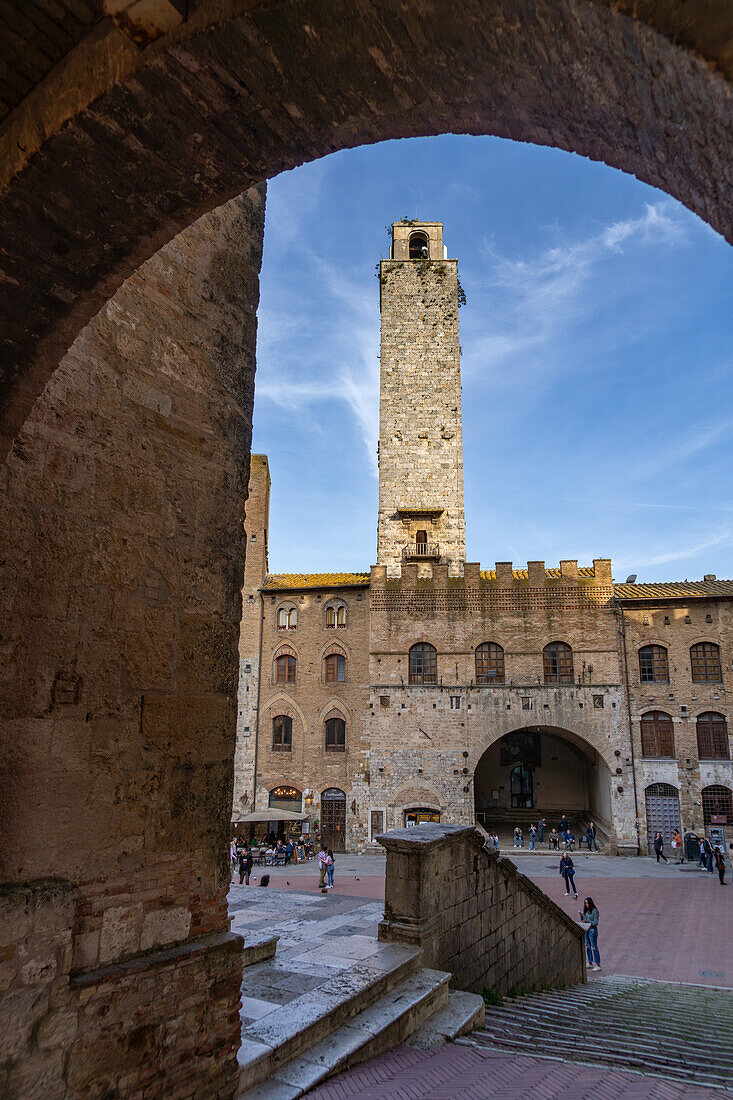 Tourists on the Piazza del Duomo with Torre Rognosa in the medieval walled city of San Gimignano, Italy.