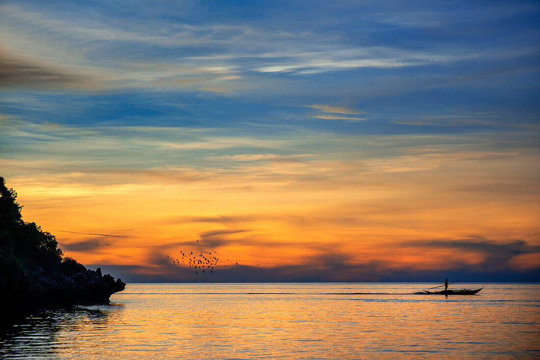 Sonnenuntergang am weißen Sandstrand mit einem einheimischen Fischer am Langub Beach auf der Insel Malapascua, Cebu, Philippinen