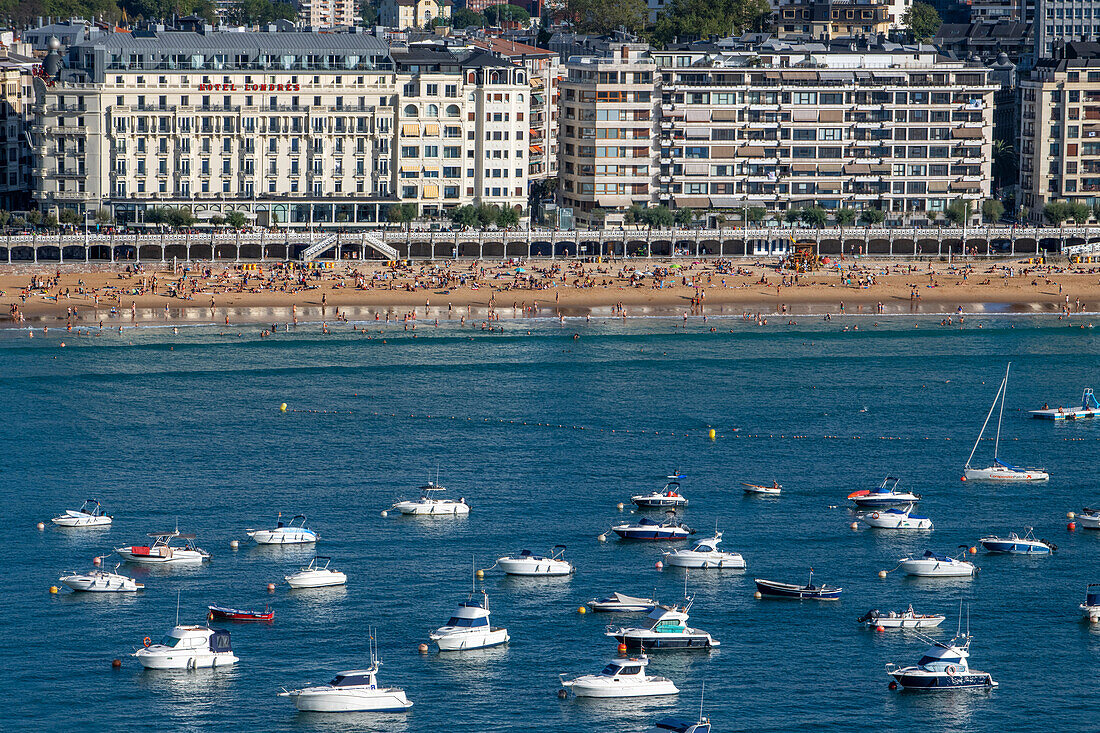 Playa de la Concha beach and fishing boats and sport fishing boats to recreational boat fishing are moored in the harbor of Donostia San Sebastian.