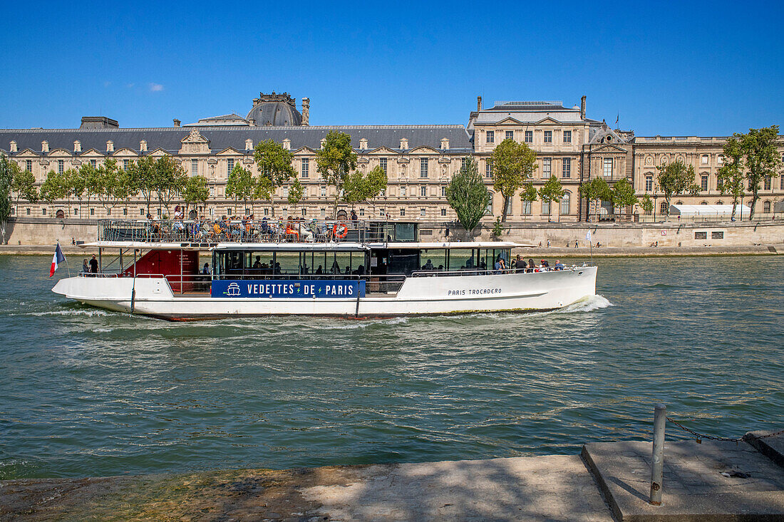 Passenger touristic cruise ship in the Seine river is moored to the pier near Louvre museum