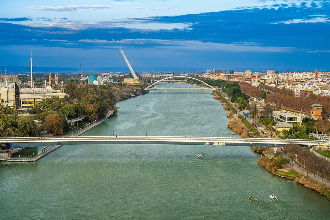 A scenic view of Seville featuring the Guadalquivir River and iconic city bridges.