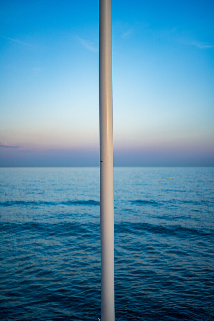 A tranquil seascape with clear sky, featuring a lamppost in Nerja, Spain.