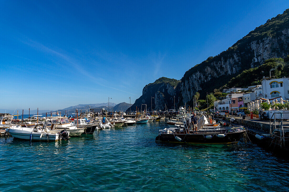 Small boats docked in the harbor of Marina Grande on the island of Capri, Italy. The Sorrento Peninsula is behind.