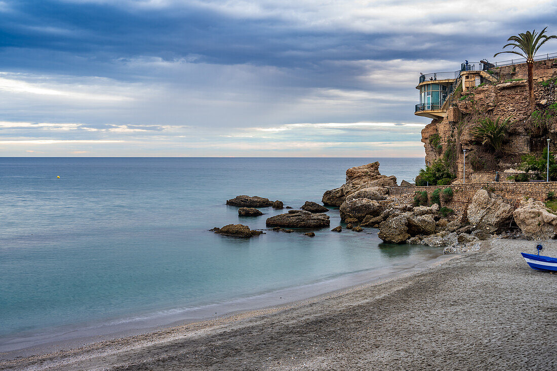 Long exposure view of Balcon de Europa, coastline, and calm sea during sunset in Nerja.