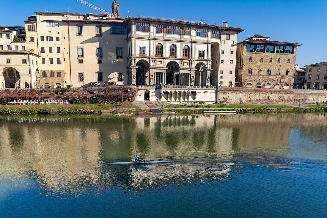 A rower in a scull on the river Arno passes the Uffizi Gallery in Florence, Italy.