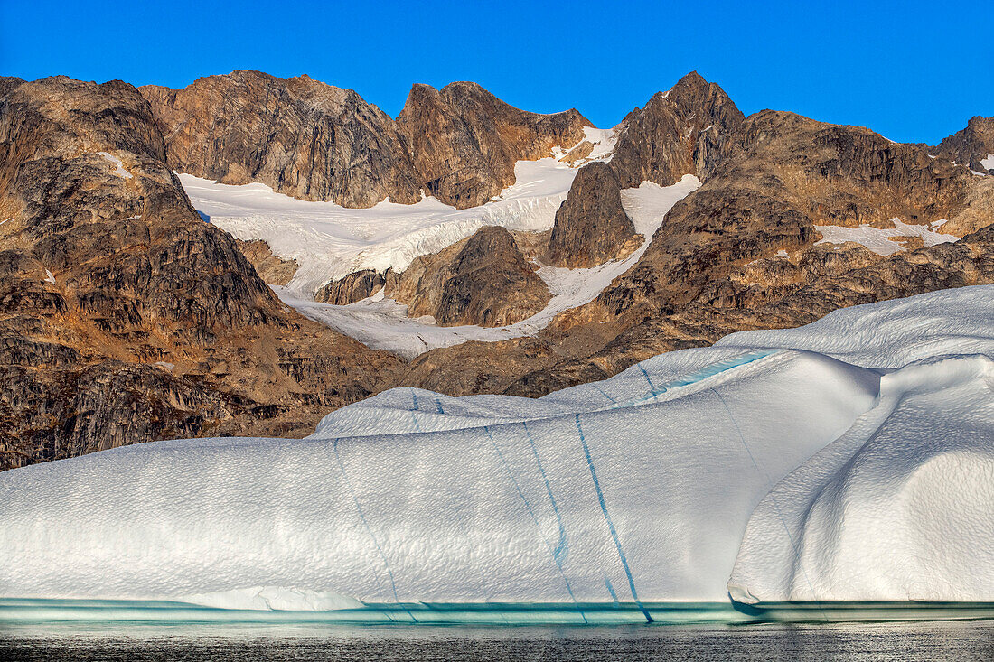 Skjoldungen Fjord. Large iceberg in scenic fjord surrounded by snow-capped mountains, Southeast coast, Greenland