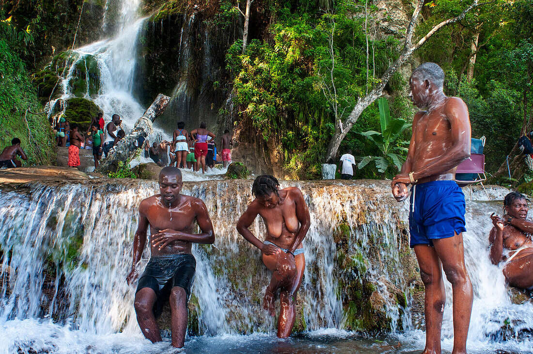 Haiti Voodoo Festival in Saut d'Eau, in Saut d'Eau, Ville Bonheur, Haiti. Tausende von Vodou- und katholischen Anhängern versammelten sich unter dem Wasserfall von Saut d'Eau in Haiti. Die Wallfahrt, die sowohl von Voodou-Anhängern als auch von Katholiken unternommen wird, hat ihren Ursprung in der Sichtung des Bildes der Jungfrau Maria auf einem Palmblatt in der Nähe des Wasserfalls vor einem halben Jahrhundert. Der Katholizismus und die Voodou-Praktiken sind in ihrer haitianischen Form für immer miteinander verwoben. Das Erscheinen eines Regenbogens unter den Wasserfällen soll bedeuten, dass