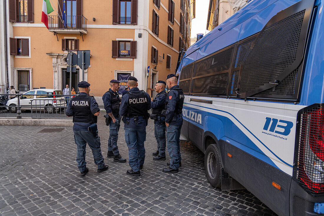 Eine Gruppe bewaffneter Polizisten mit einem Polizeiwagen auf der Piazza Colonna in Rom, Italien.