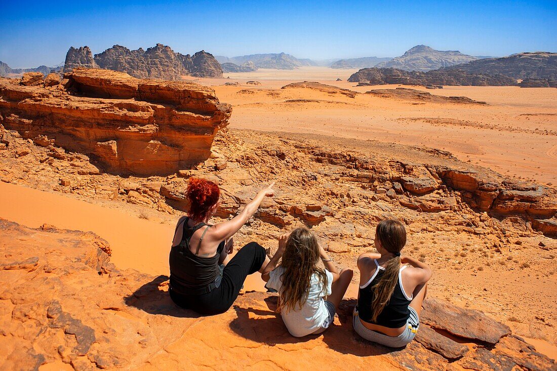 Family looking over the red sands of the desert of Wadi Rum in the sunset time, Jordan