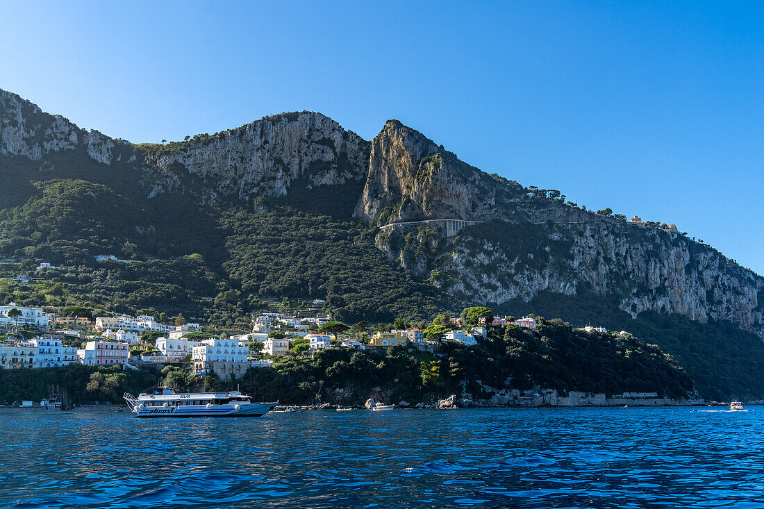 View of the port of Marina Grande on the island of Capri, Italy. Viewed from the Bay of Naples. A high-speed passenger ferry is anchored off shore.