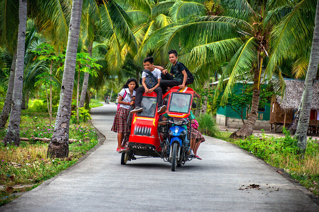 Local students, fanny many people driving a motorcyce in Sipaway Island, San Carlos City, Negros Occidental, Philippines