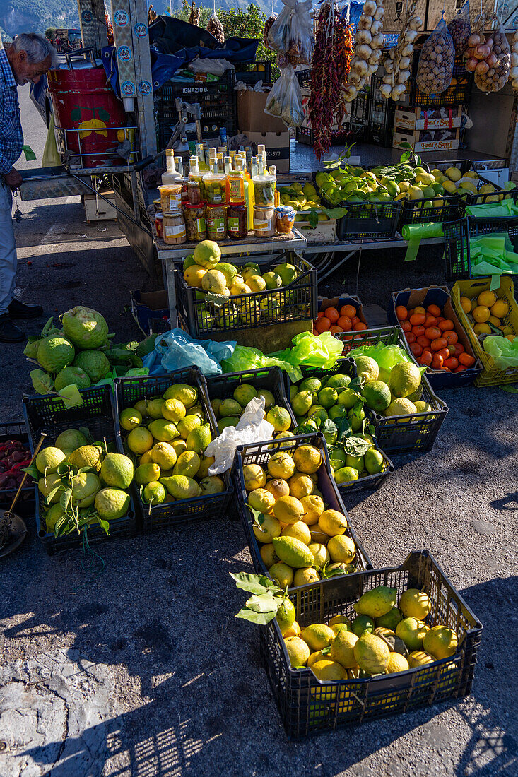 A roadside vendor selling fresh produce to a family by the Amalfi Coast road near Positano, Italy.