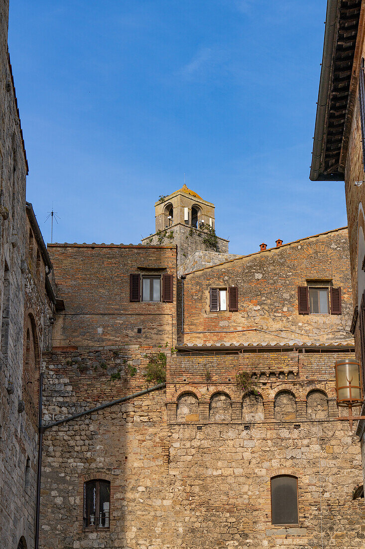 Die Spitze des Torre Rognosa über den Gebäuden der Via San Giovanni in der mittelalterlichen Stadt San Gemignano, Italien.