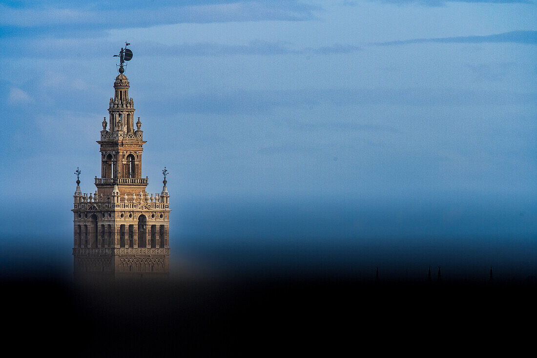 Atemberaubender Blick auf den Glockenturm Giralda in Sevilla, Spanien, unter einer blauen Atmosphäre.