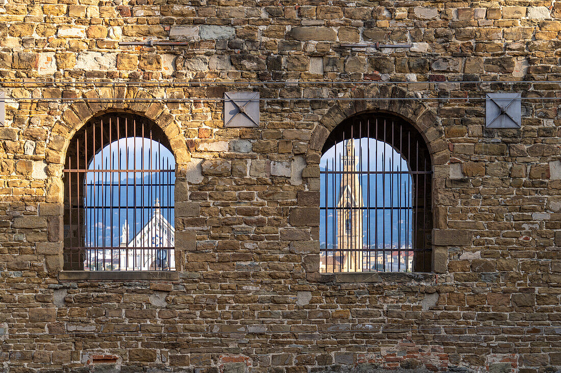 The Basilica of Santa Croce framed by the barred windows of the Palazzo Vecchio in Florence, Italy.