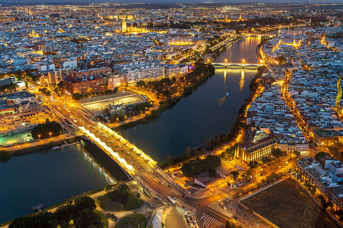 Helle Lichter beleuchten den Fluss Guadalquivir und das pulsierende Stadtzentrum von Sevilla und zeigen die Schönheit des Nachthimmels.