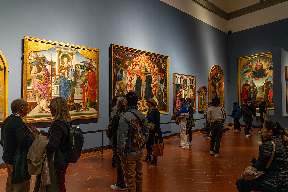 Visitors viewing Renaissance paintings in an exhibition hall in the Accademia Gallery in Florence, Italy.