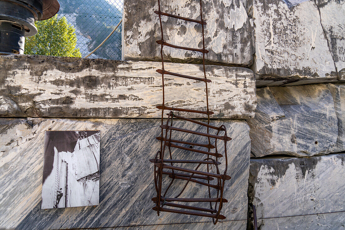 Eine alte Drahtleiter, die von Bergleuten in den Steinbrüchen verwendet wurde. Steinbruchmuseum Fantiscritti, Carrara, Italien. Links ist ein altes Foto einer Leiter im Einsatz zu sehen.