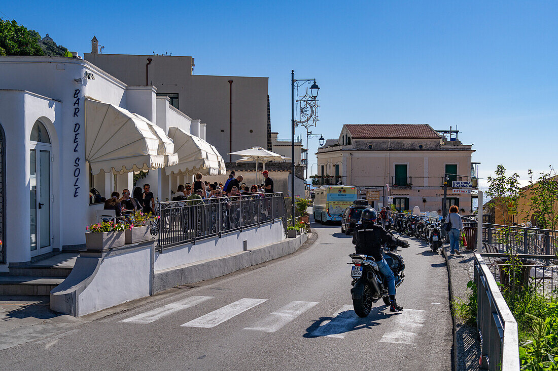 Traffic on SS163, the Amalfi Coast road in Vettica Maggiore, Praiano, Italy. Tourists dine al fresco.