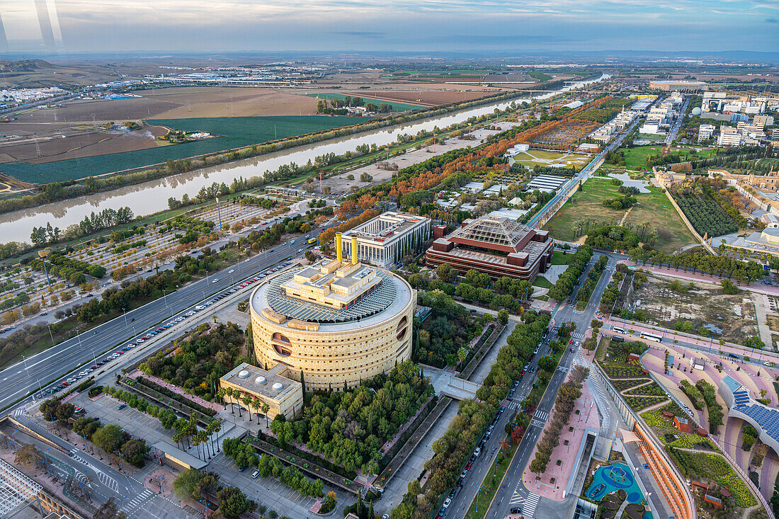 Der Torre Triana erhebt sich in Sevilla, mit dem Fluss Guadalquivir und der üppigen Vegetation und Architektur von Aljarafe im Hintergrund.